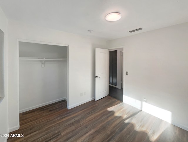 unfurnished bedroom featuring a closet and dark wood-type flooring