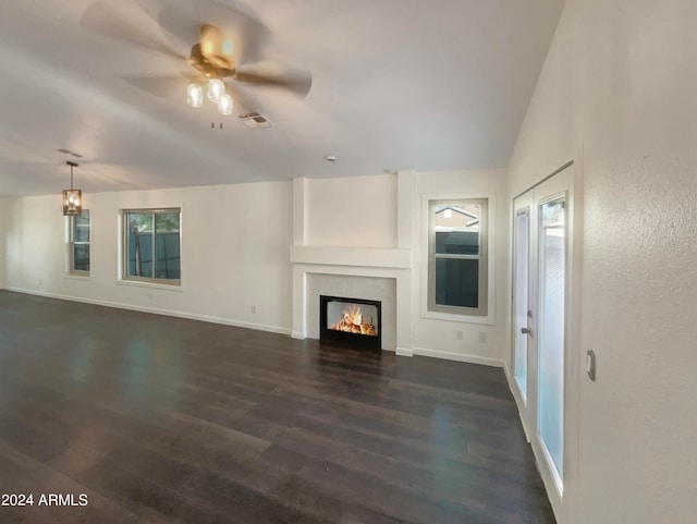 unfurnished living room featuring ceiling fan, dark hardwood / wood-style floors, a fireplace, vaulted ceiling, and plenty of natural light