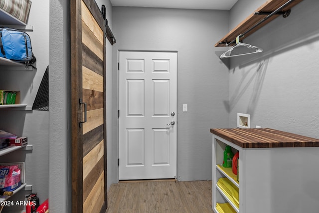 laundry room featuring washer hookup, a barn door, and light hardwood / wood-style floors