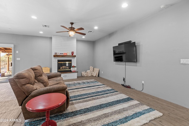 living room featuring ceiling fan and a large fireplace