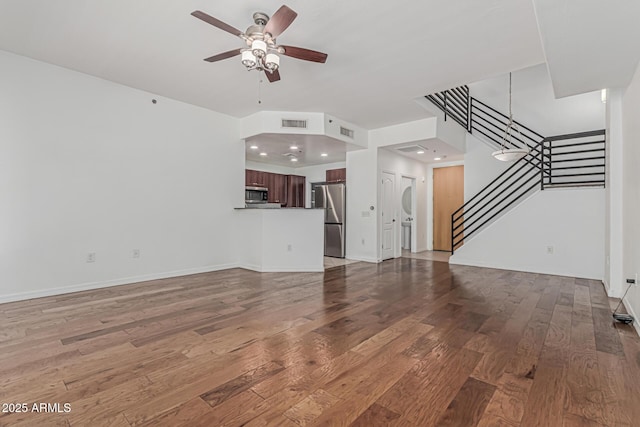 unfurnished living room with visible vents, ceiling fan, hardwood / wood-style flooring, and stairway