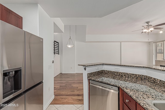 kitchen featuring light tile patterned flooring, baseboards, ceiling fan, dark stone counters, and appliances with stainless steel finishes