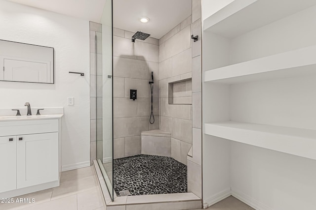 bathroom with vanity, tile patterned flooring, baseboards, tiled shower, and recessed lighting