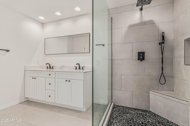 bathroom with double vanity, baseboards, recessed lighting, a sink, and a tile shower