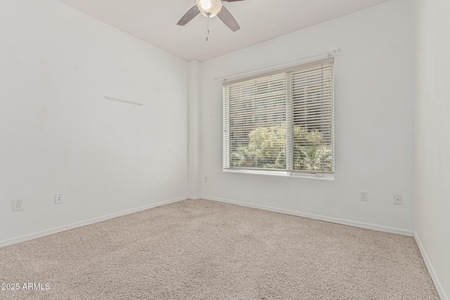 carpeted empty room featuring ceiling fan and baseboards