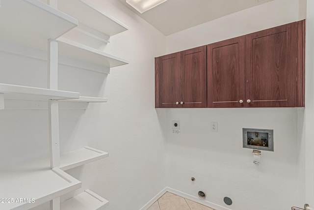 clothes washing area featuring gas dryer hookup, washer hookup, hookup for an electric dryer, cabinet space, and light tile patterned floors