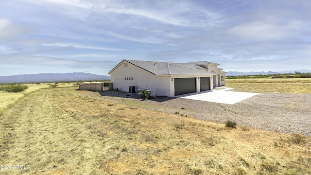 exterior space featuring a mountain view, cooling unit, a rural view, and a garage