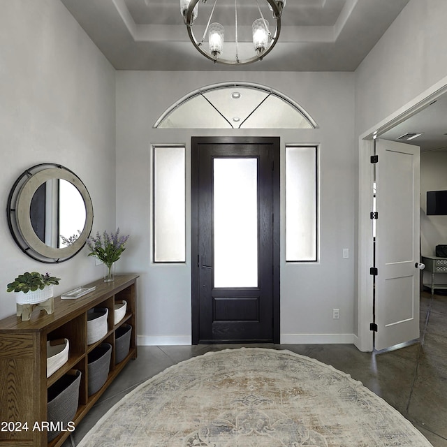 entrance foyer with a tray ceiling and a notable chandelier