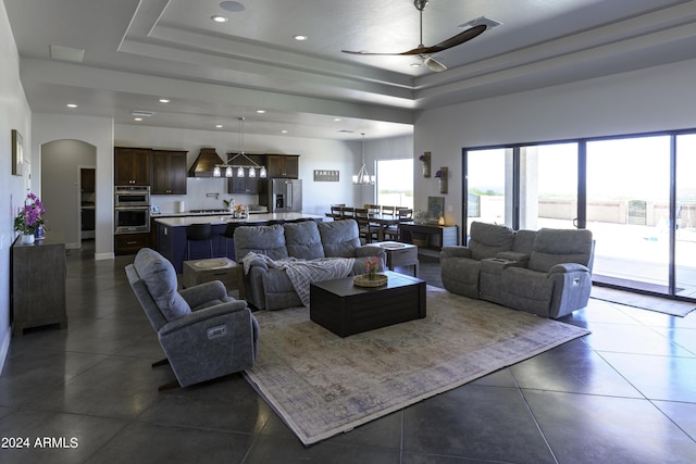 living room with ceiling fan and a tray ceiling