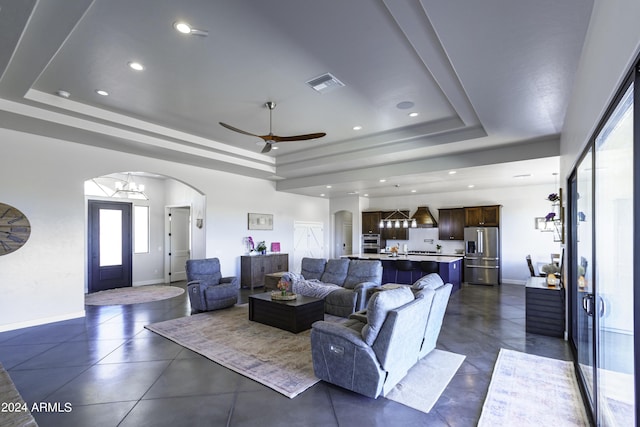 living room with ceiling fan and a raised ceiling