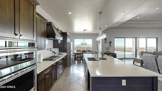 kitchen with a center island with sink, wall chimney exhaust hood, sink, and appliances with stainless steel finishes