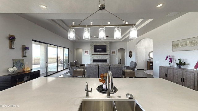 kitchen with a tray ceiling, a stone fireplace, and sink