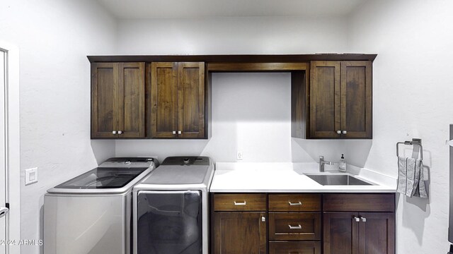 laundry room featuring washing machine and clothes dryer, sink, and cabinets