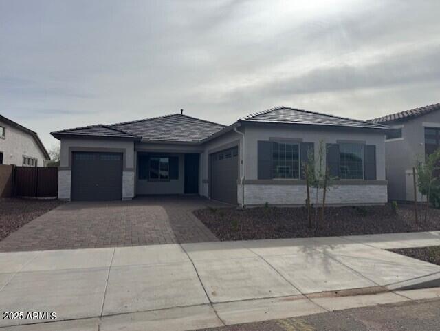 view of front of house with decorative driveway, a garage, and stucco siding