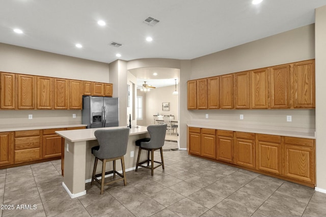 kitchen featuring arched walkways, visible vents, stainless steel fridge, and light countertops