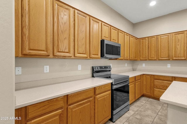 kitchen featuring appliances with stainless steel finishes, light tile patterned flooring, and light countertops