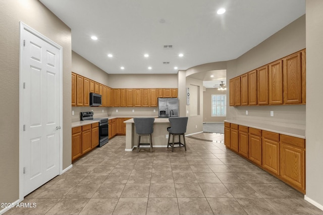 kitchen featuring visible vents, a breakfast bar, a center island, appliances with stainless steel finishes, and light countertops