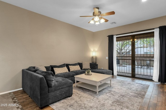 living area featuring visible vents, ceiling fan, baseboards, and wood finished floors