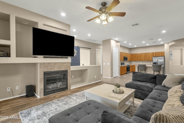 living area with light wood finished floors, recessed lighting, a fireplace, and baseboards