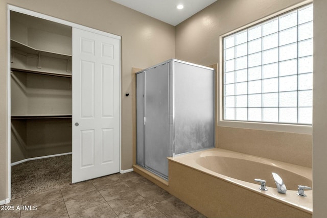 bathroom featuring a bath, a shower stall, tile patterned floors, and a walk in closet