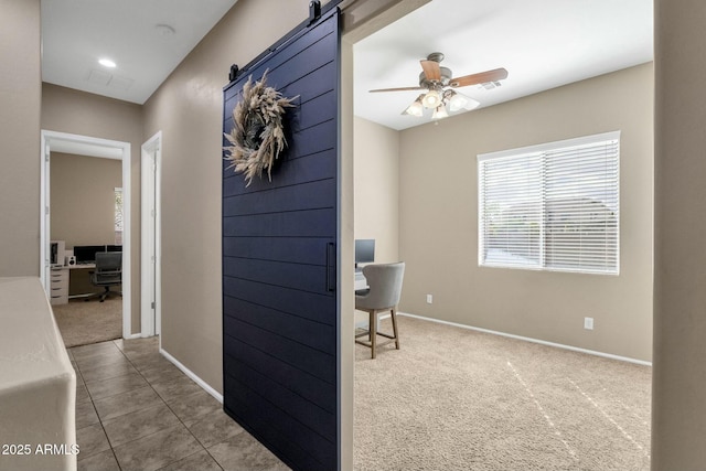 interior space featuring a barn door, carpet, and baseboards