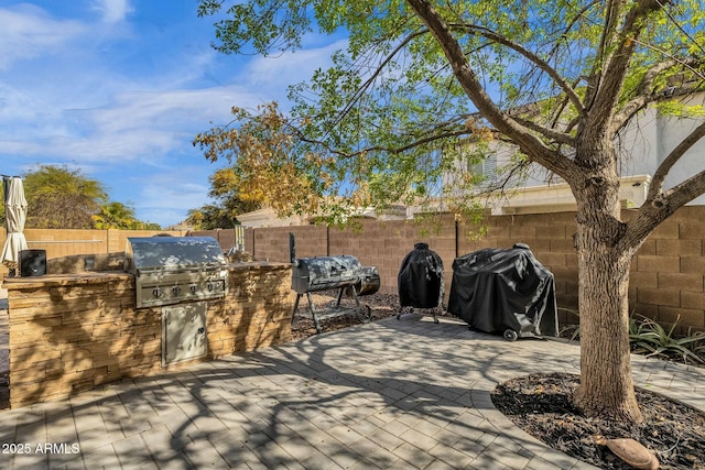 view of patio featuring exterior kitchen, a fenced backyard, and a grill