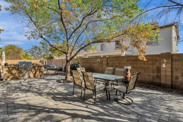 view of patio with outdoor dining space, exterior kitchen, a fenced backyard, and grilling area