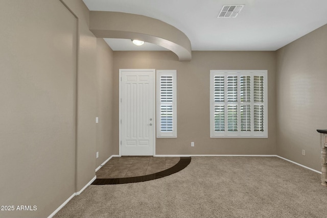 foyer entrance with arched walkways, visible vents, carpet floors, and baseboards