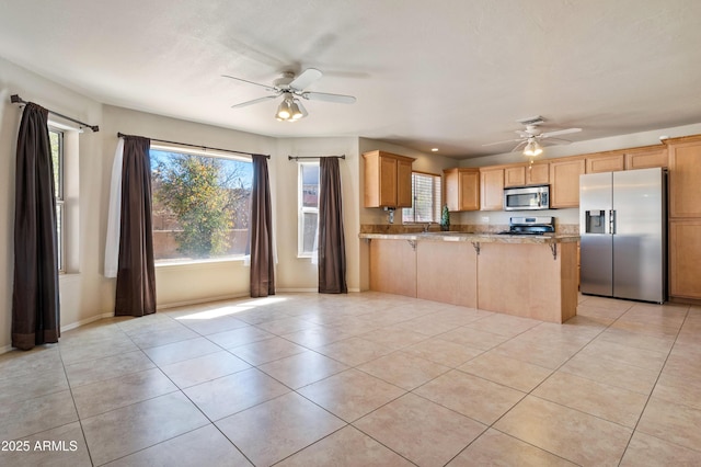 kitchen with ceiling fan, stainless steel appliances, kitchen peninsula, and a breakfast bar area