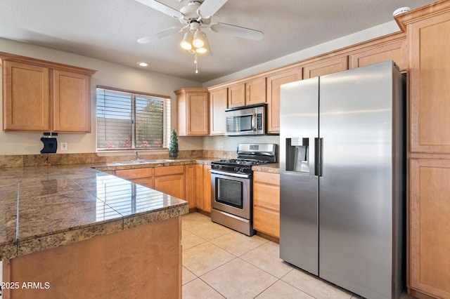 kitchen with light tile patterned floors, sink, ceiling fan, stainless steel appliances, and kitchen peninsula