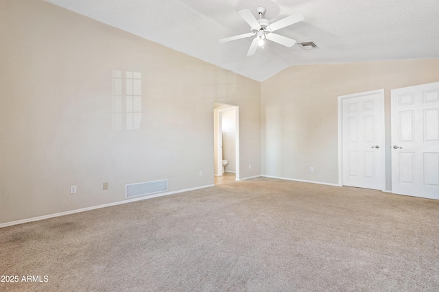 interior space with lofted ceiling, ensuite bath, a textured ceiling, carpet floors, and ceiling fan