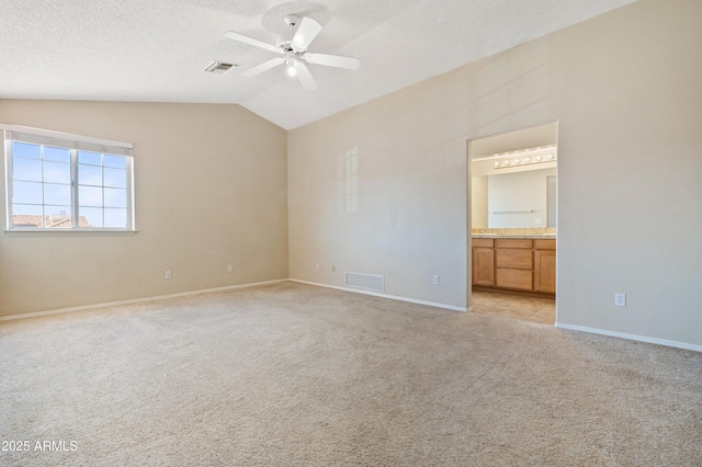 spare room featuring lofted ceiling, ceiling fan, light colored carpet, and a textured ceiling