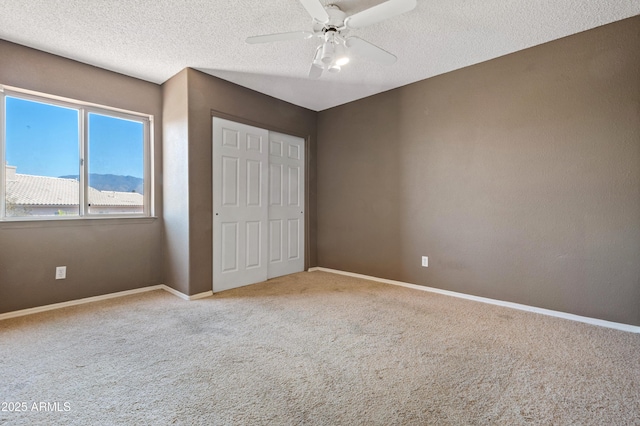 unfurnished bedroom with ceiling fan, light colored carpet, a closet, and a textured ceiling