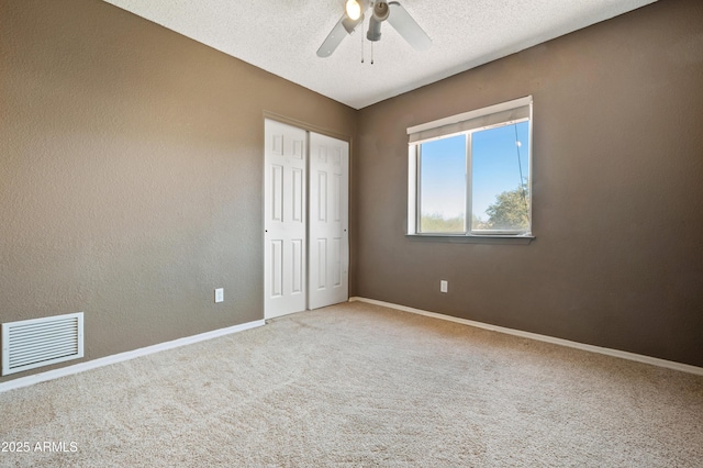 unfurnished bedroom with ceiling fan, carpet flooring, a textured ceiling, and a closet