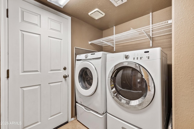 laundry area featuring washing machine and clothes dryer and a textured ceiling