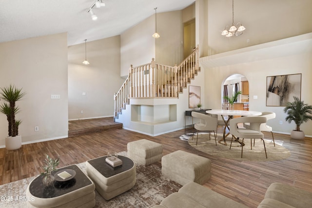 living room featuring a high ceiling, rail lighting, hardwood / wood-style floors, and an inviting chandelier