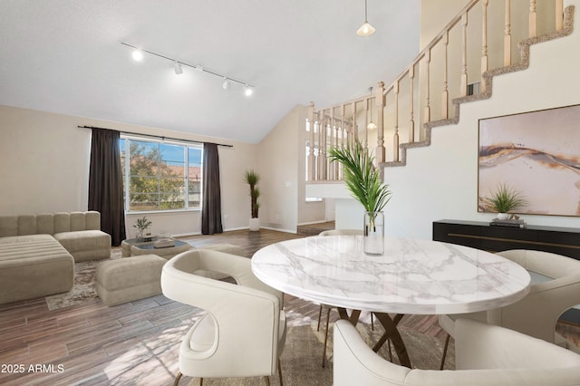 dining area featuring vaulted ceiling, wood-type flooring, and track lighting