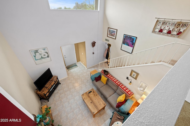 living area with tile patterned floors, stairway, and a towering ceiling