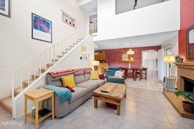 tiled living room featuring stairway, a brick fireplace, and a high ceiling