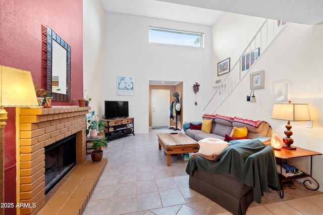 living room with tile patterned flooring, stairway, a fireplace, and a towering ceiling