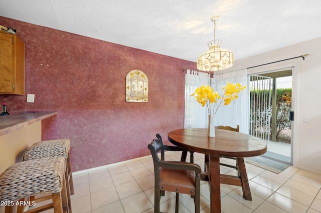 dining room featuring light tile patterned floors, a textured ceiling, wallpapered walls, and baseboards