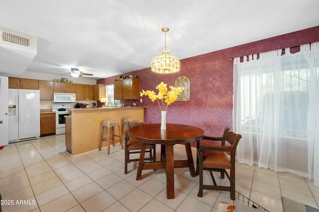 dining room featuring wallpapered walls, light tile patterned flooring, a ceiling fan, and visible vents