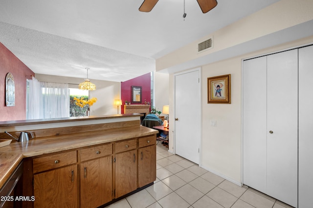 kitchen featuring visible vents, brown cabinets, a textured ceiling, light countertops, and light tile patterned floors