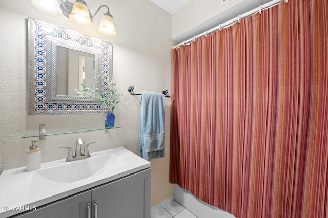 bathroom featuring tile patterned flooring, vanity, and a textured wall