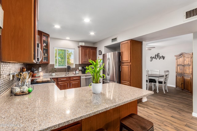 kitchen featuring kitchen peninsula, a breakfast bar, light hardwood / wood-style floors, and appliances with stainless steel finishes