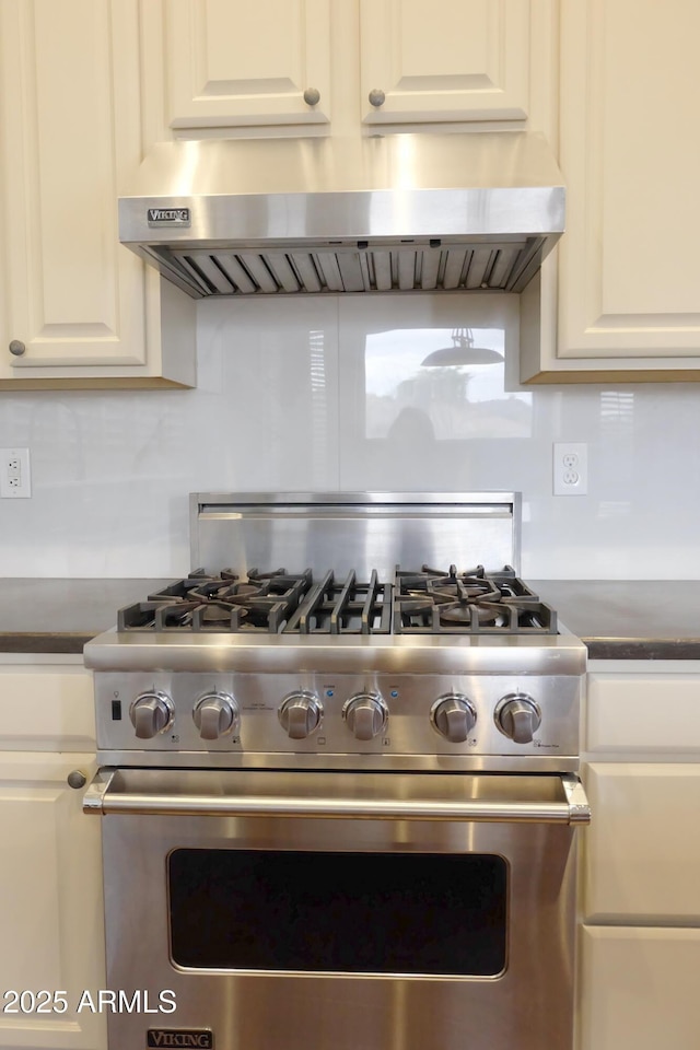 kitchen featuring white cabinetry, dark countertops, high end range, and exhaust hood