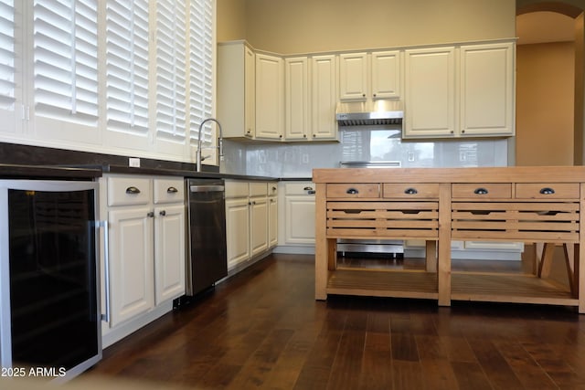 kitchen featuring dark wood-type flooring, wine cooler, decorative backsplash, arched walkways, and white cabinetry