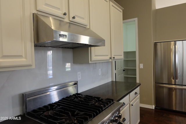 kitchen featuring under cabinet range hood, dark countertops, tasteful backsplash, appliances with stainless steel finishes, and white cabinets