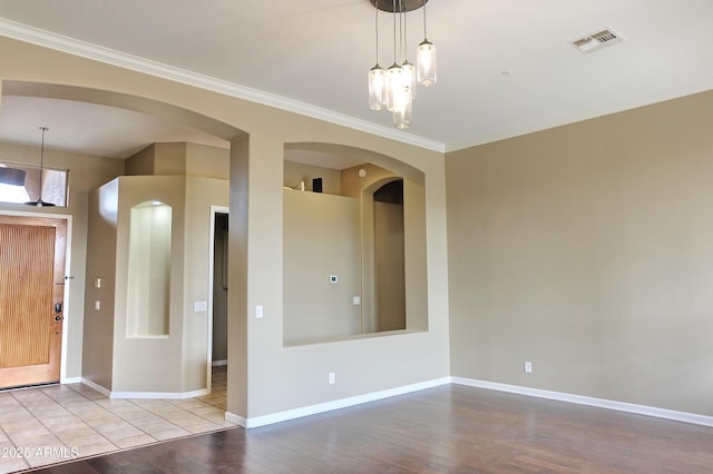 spare room featuring wood finished floors, visible vents, and ornamental molding