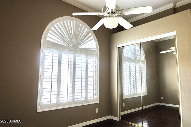 unfurnished bedroom featuring ornamental molding, dark wood-style floors, a closet, baseboards, and ceiling fan